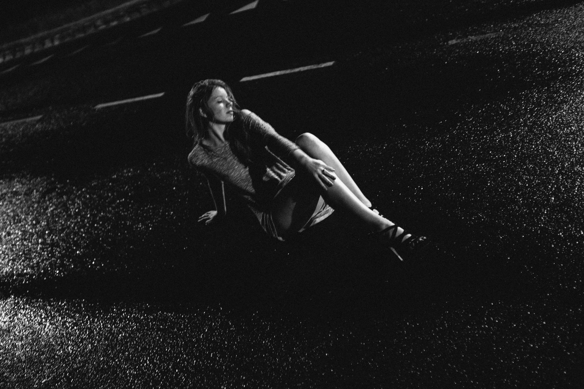 Vrouw zit op natte straat in zwart-witfoto