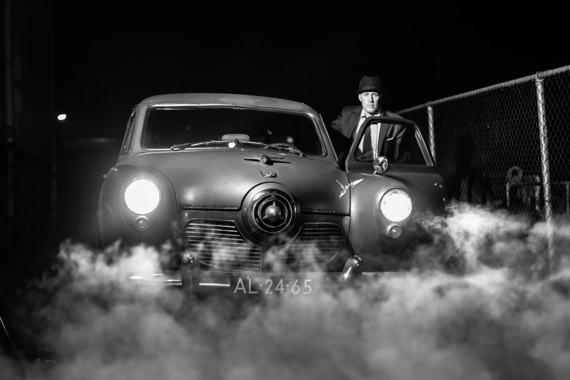 Vintage auto met man in rook, zwart-wit filmstijl