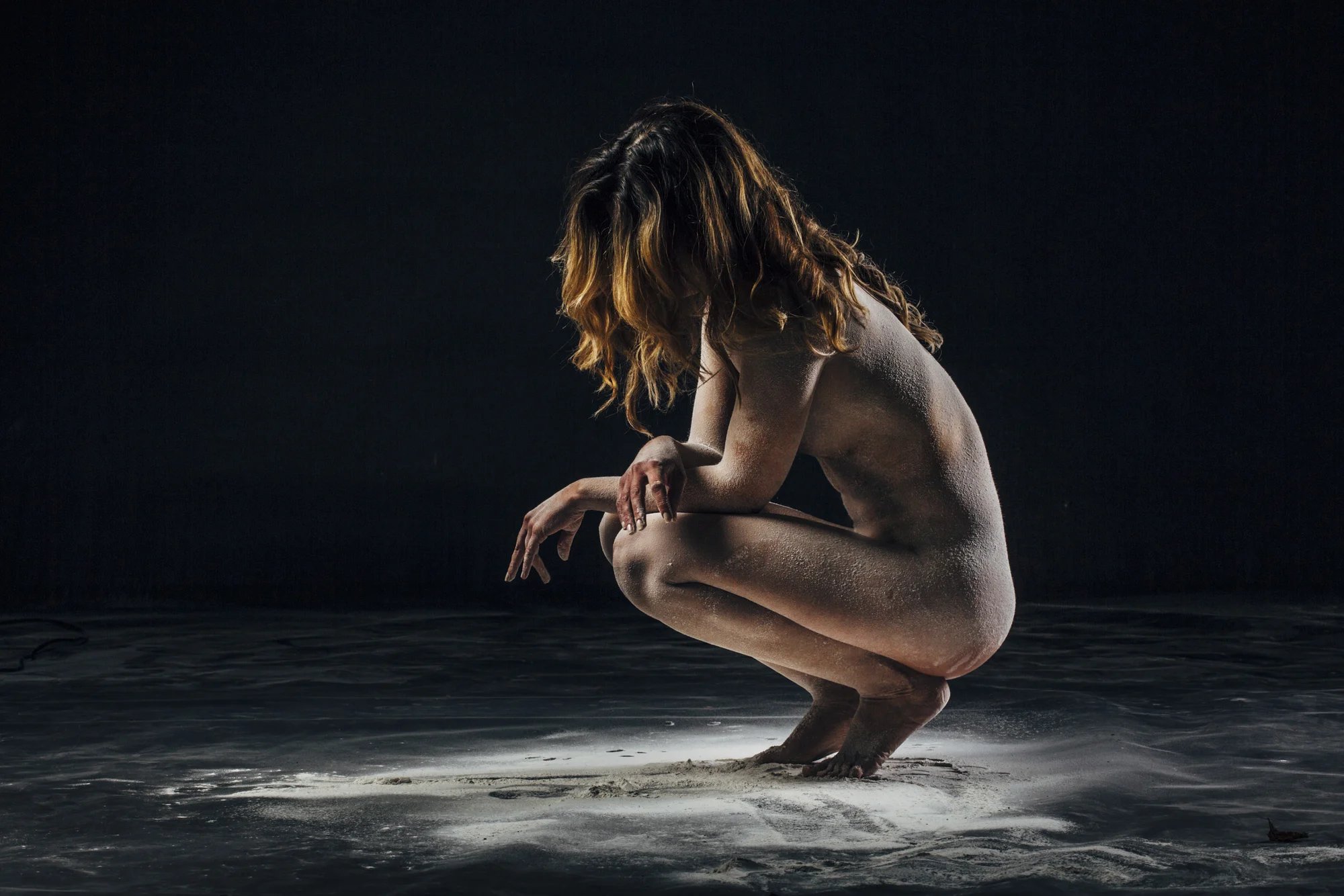 Persoon in kniepositie onder dramatische spotlighting